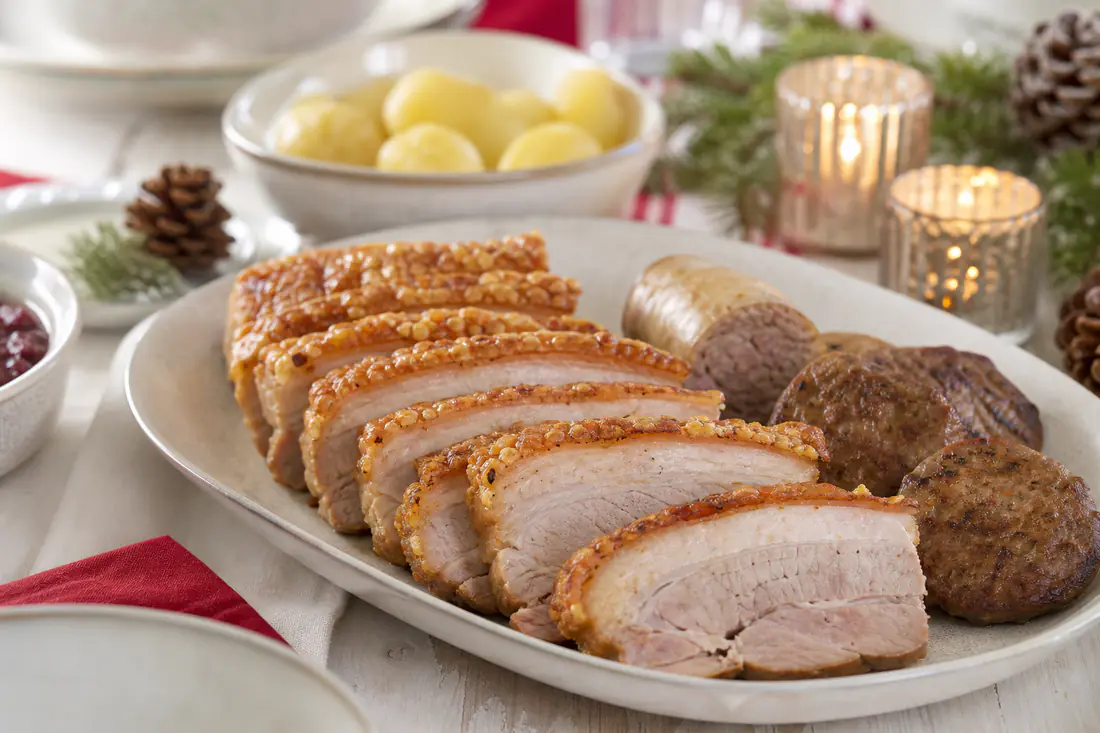 Julebord med ribbe med sprø svor, medisterkaker, julepølse, surkål og poteter på fat