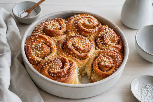 Åtte gyldne kanelboller i en rund form, med kanelsmør som lekker ut og perlesukker på toppen