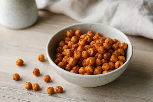 Sprø ristede kikerter med paprika i en liten skål, med noen kikerter strødd utover bordet