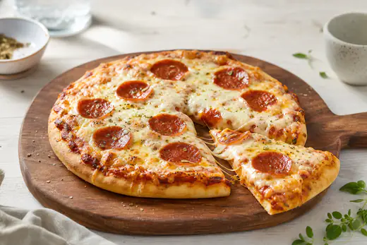 Liten hjemmelaget pizza med smeltet mozzarella, pepperoni og oregano på et trebrett