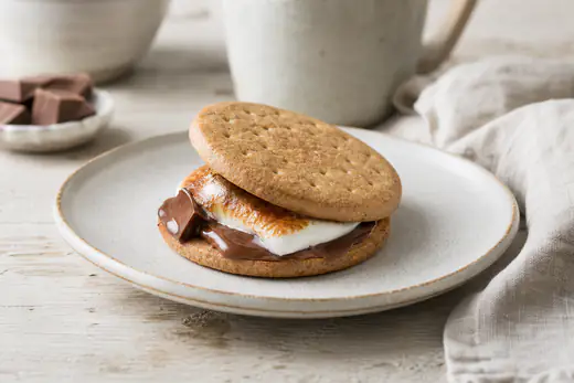S'mores med gylne ristede marshmallows og smeltet sjokolade mellom to kjeks, på en tallerken
