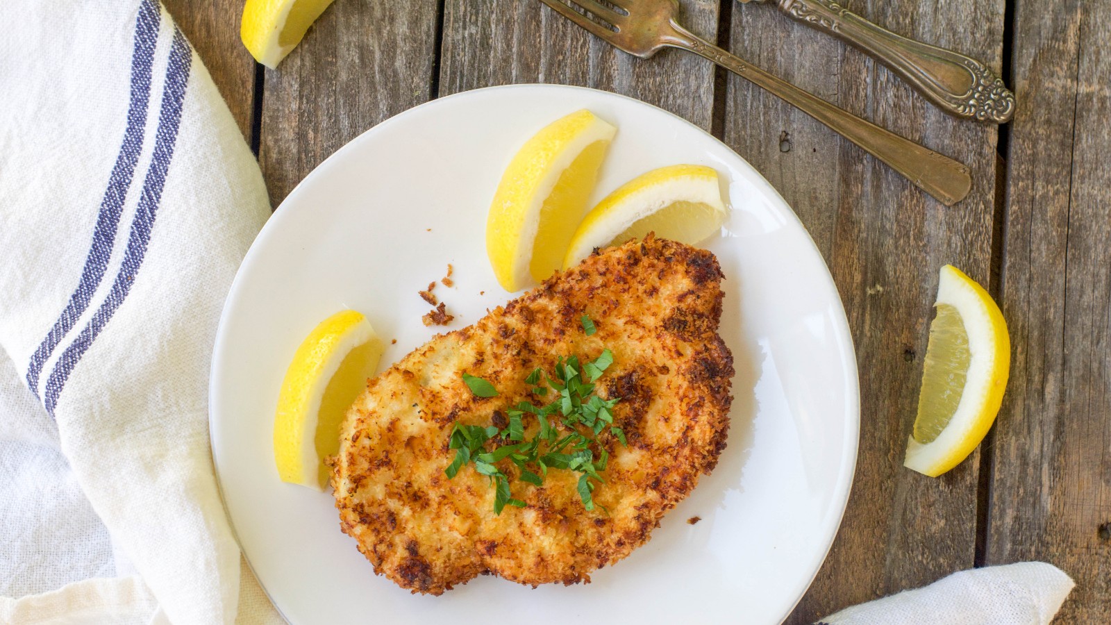 Sprø schnitzel i airfryer servert med sitronskiver og potetsalat.
